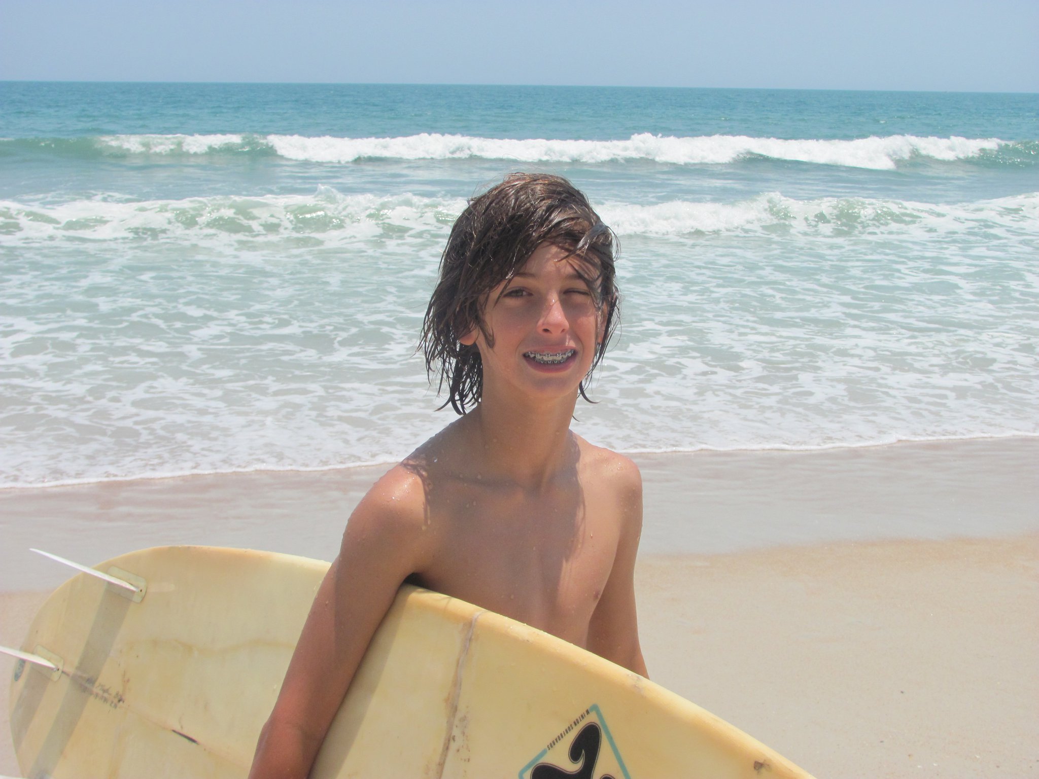 boy walking on beach with surfboard