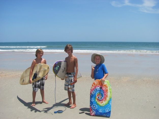 476463_10150644475057964_1463684071_o three boys holding surfboards on the beach